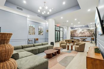 A spacious living room with a large wicker chair and a green sofa. at LiveWell Apartments, Pittsburgh, PA